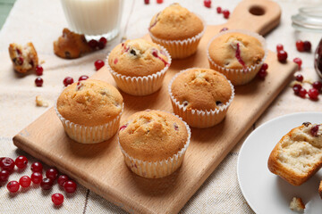 Wooden board with delicious cranberry muffins on table