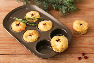 Baking tray with tasty mince pies on wooden table