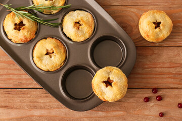 Baking tray with tasty mince pies on wooden table