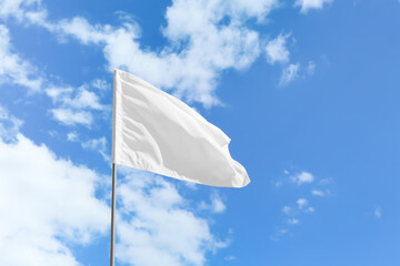 Waving white flag against blue sky