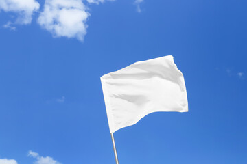 Waving white flag against blue sky