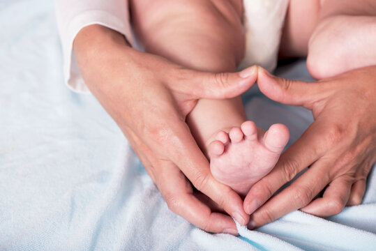 Children's feet in heart-shaped hands of mother. Happy Family concept. Beautiful conceptual image of Motherhood
