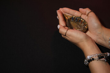 Female hands with diya lamp for Diwali on dark background