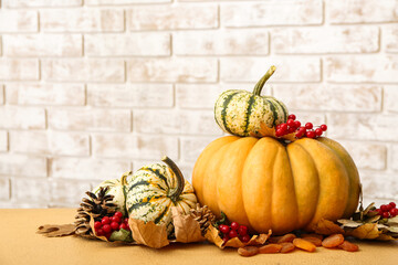 Festive autumn composition with pumpkins on table against brick wall