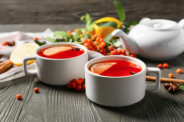 Cups of hot rowan tea on wooden background