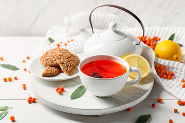 Composition with cup of rowan tea and cookies on table