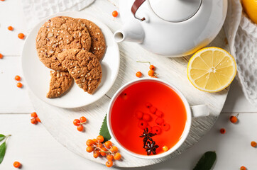 Composition with cup of rowan tea and cookies on light wooden background, closeup