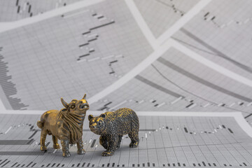 Metallic yellow bull and bear figures on the background of stock price charts. Exchange trade...