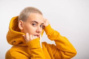 Young woman in an ocher hood on a white background.