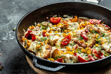 Roasted potato in frying pan, with onions, corn, tomatoes, bacon and cheese. top view