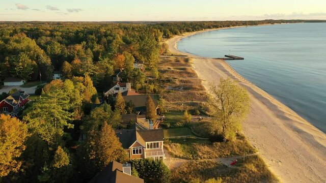 Aerial view of beachfront houses. Establishing shot of waterfront homes. Sunset sunrise sunlight,  Fall Autumn colorful trees. Midwest USA, Door county Wisconsin, lake Michigan.