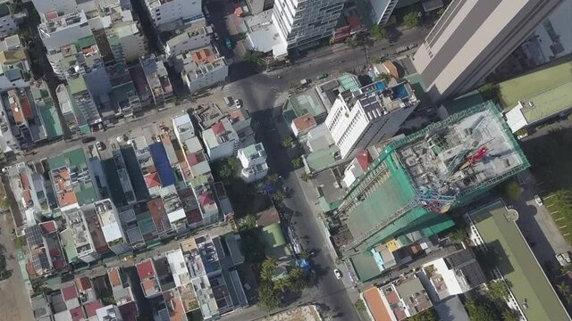 Contemporary city streets with construction site of modern skyscraper with crane and driving cars on sunny day aerial view
