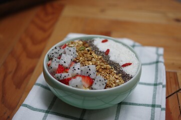 Granola yoghurt bowl with cereal strawberry pitaya fruits coconut flake and lycium chinense on green napkin