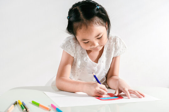 A little toddler girl doing arts and crafts work at home drawing sketching with colorful paint using color pencil. Child education at home during a lockdown. Concept of art and creativity of children
