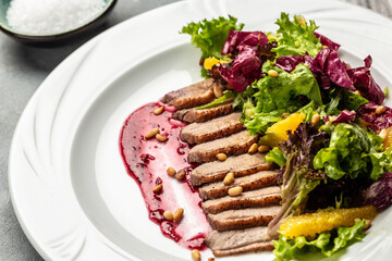 Appetizing baked sliced duck fillet with berry sauce and and salad, Delicious balanced food concept