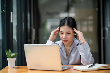 Asian businesswoman gets stressed while having a problem at work in the office.