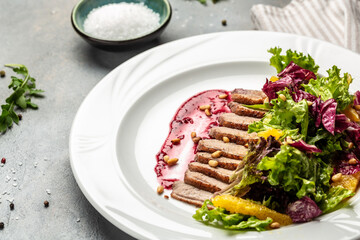 Salad with baked duck, green salad mix and berry sauce