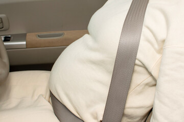 A young Asian pregnant woman wears a searbelt appropriately and drives a car - obrazy, fototapety, plakaty