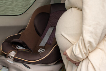 A young pregnant Asian woman sets a car seat for her new baby