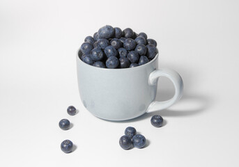 Blueberries in a large cup bowl on a white background. Side view