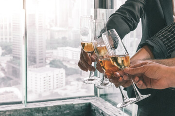 Business team celebrating their success together by making a toss with a champagne glass. They are wearing suit and white shirt.