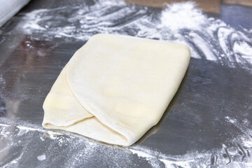 Rolled out puff pastry on a table with flour. Workpiece for pastry