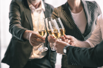 Business team celebrating their success together by making a toss with a champagne glass. They are wearing suit and white shirt.