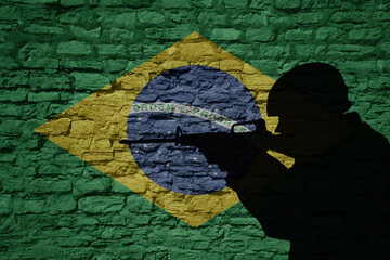 Soldier silhouette on the old brick wall with flag of brazil country.