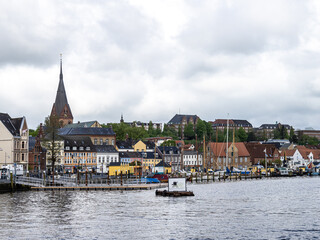 Fototapeta premium Sail boats in the port of Flensburg, St. Jorgen's Church in the background. Schleswig-Holstein in Germany