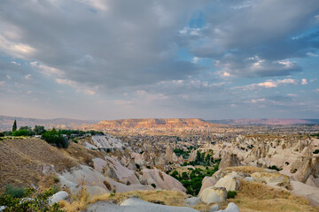 Wide angle photo in Cappadocia, Goreme with overcast and cloudy sky, geology formation of and sun lights on small hill