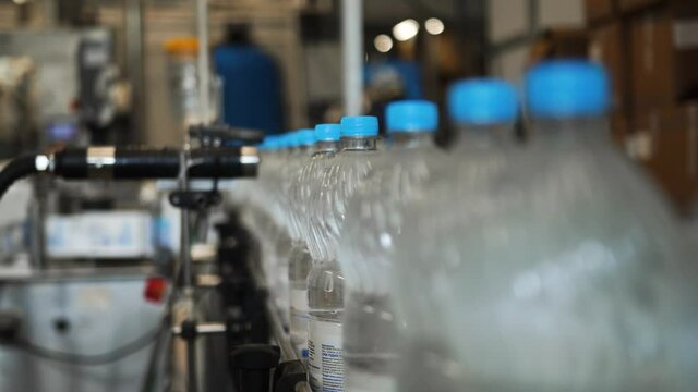 Production, bottling plant for drinking carbonated water. Automated line, sticker, stamping of labels, emblems with roller of the manufacturer's brand on plastic bottles, containers with spring water.
