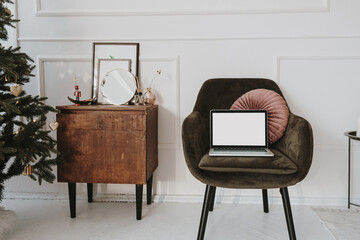 Front view of laptop computer with blank screen mockup copy space on comfortable lounge chair. Work...
