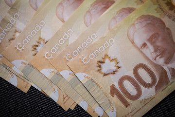 Multiple 100 Canadian dollar bills on the table. Counting cash on the table. Emptying wallet for...