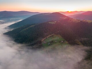 Fog in the mountain valley at dawn. Ukrainian Carpathians in the morning in the haze. Aerial drone...
