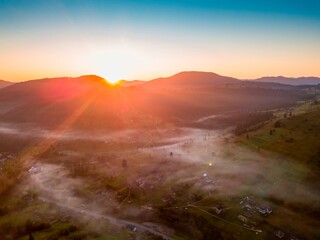 Fog in the mountain valley at dawn. Ukrainian Carpathians in the morning in the haze. Aerial drone...
