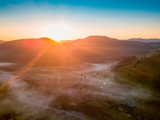 Fog in the mountain valley at dawn. Ukrainian Carpathians in the morning in the haze. Aerial drone...