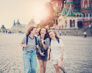 Fototapeta na wymiar Three young women students friends happily walking travelling along Red Square in Moscow