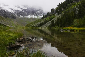 reflections in a clear mountain lake with snow on a high mountain in the background