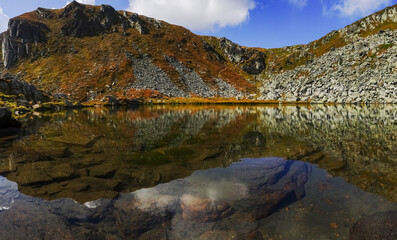 reflection from colorful mountains in a clear mountain lake panorama