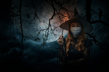 Halloween witch wearing medical face mask holding magic wand standing over dead tree, full moon, bird and spooky cloudy sky, Halloween and coronavirus or covid-19 concept