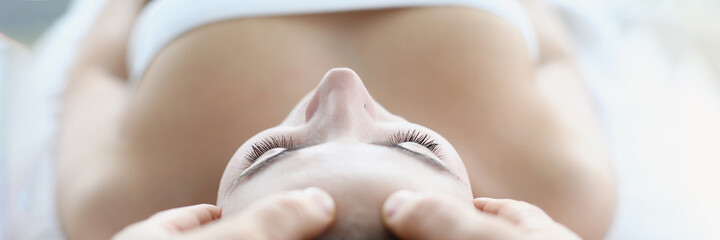 Young woman masseur makes face and head massage in spa salon