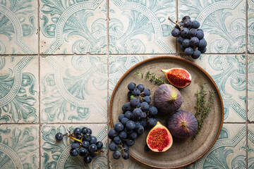 Obraz na płótnie Canvas fresh figs on plate on tile background, top view