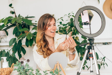 A young woman beauty blogger broadcasts live streaming to review makeup and cosmetic products on social media,reviews beauty product for video blog.Beauty concept.