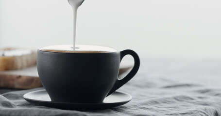 pour steamed milk into black cup making cappuccino with copy space