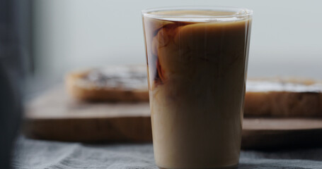 milk pour cold in brew coffee in tumbler glass on walnut table