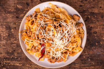 Portion of italian-american pasta with sausage stew sprinkled with grated cheese in a plate on the table, top view