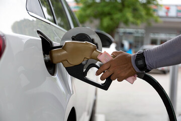 Closeup of people pumping gasoline fuel in car at gas station. Petrol or gasoline being pumped into...