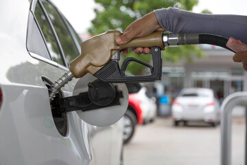 Closeup of people pumping gasoline fuel in car at gas station. Petrol or gasoline being pumped into a motor vehicle car.