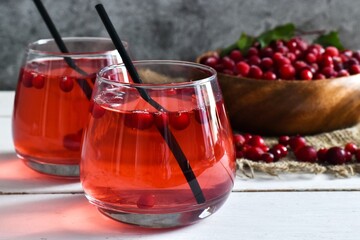 Two glasses Refreshing cocktail with cranberry and mint and bowl with cranberry, napkin on a white table. Selective focus