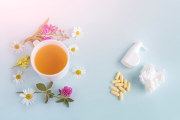 Cup of tea with flowers chamomile and blooming Sally and pills, spray for runny nose and throat. Seasonal diseases and treatment of colds, flu, heat. Herbal medicine vs conventional medicine.